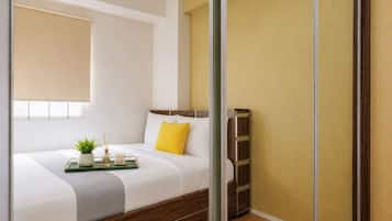 A modern bedroom with a bed, bedside table, and a window with blinds.