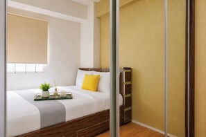 A modern bedroom with a bed, bedside table, and a window with blinds.