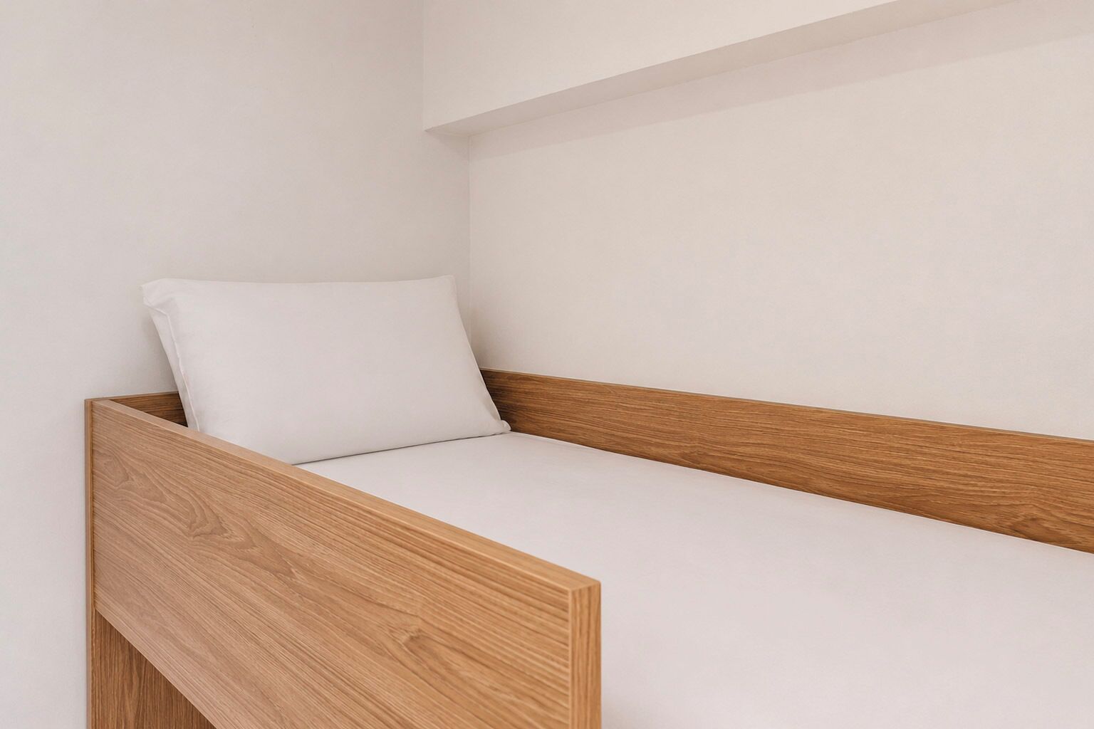 A single bed with a wooden frame and a white mattress.