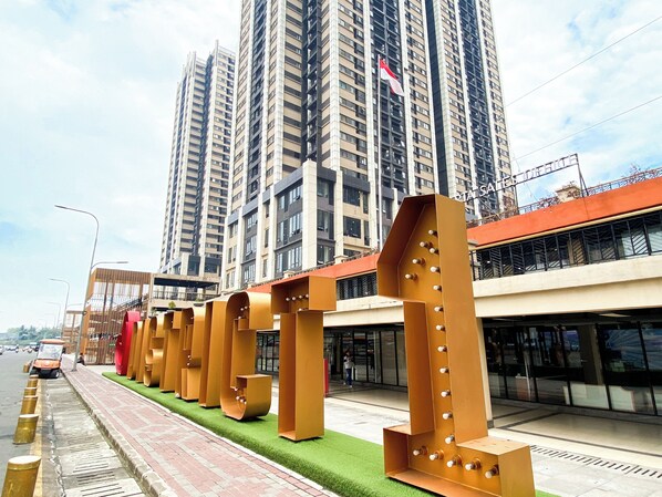 A modern urban street with high-rise buildings, a pedestrian walkway, and bollards along the road.