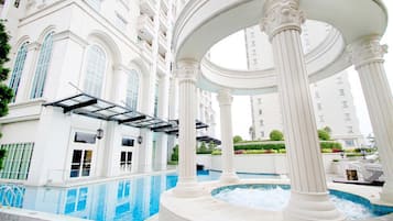 A luxurious indoor pool area with classical architecture, including columns and a pergola.