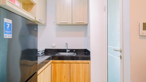 A compact kitchen with a refrigerator, sink, and wooden cabinets. - Best Choice And Restful 1Br Citralake Suites Apartment (Jakarta)