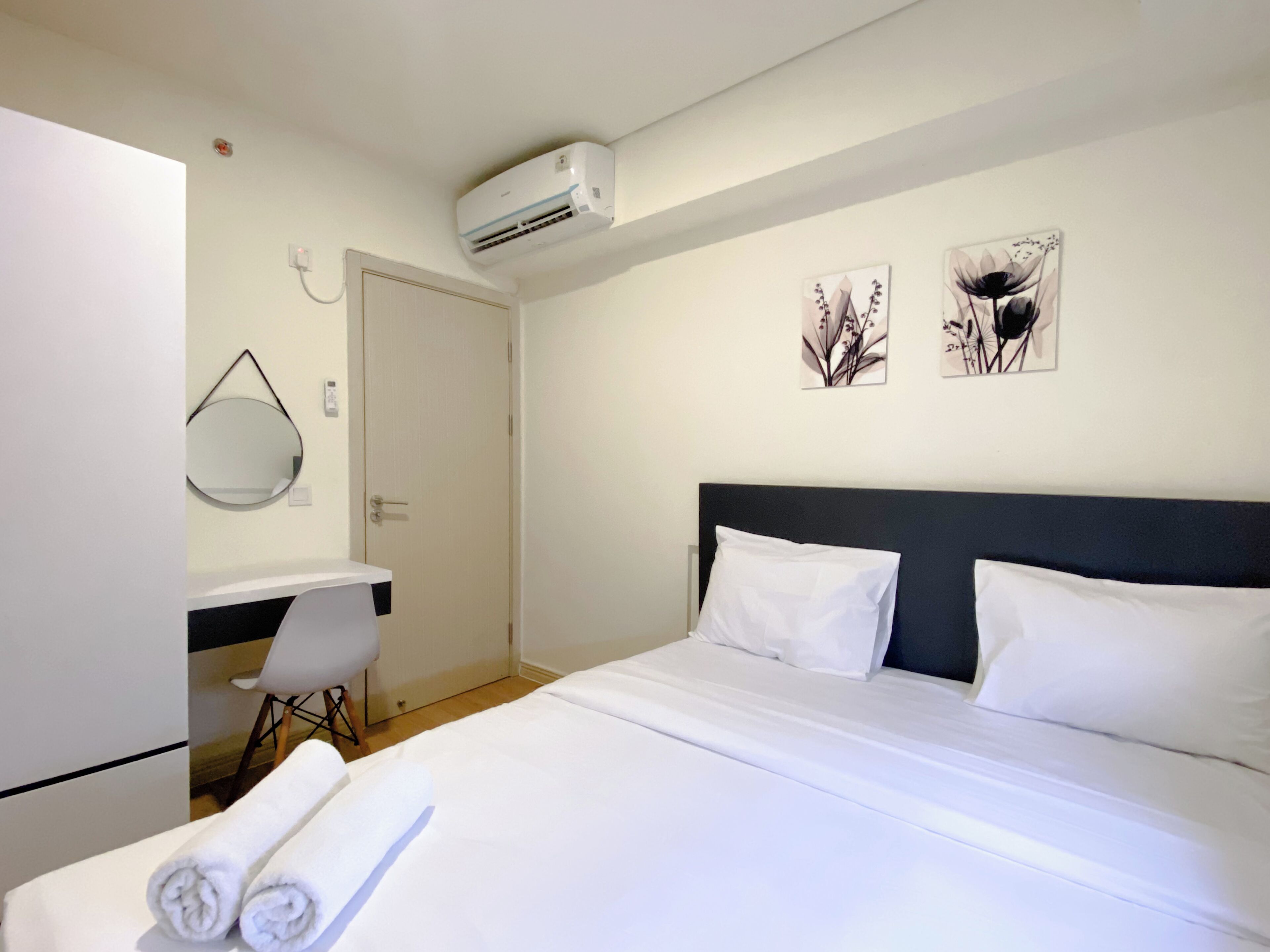 Una habitación de hotel con cama, escritorio, silla y dos obras de arte colgadas en la pared.