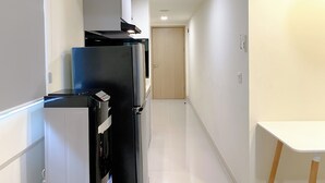 A narrow hallway with a kitchen area on one side, featuring a refrigerator, stove, and cabinets.