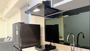 A modern kitchen with a stainless steel sink, a black refrigerator, and a built-in range hood.