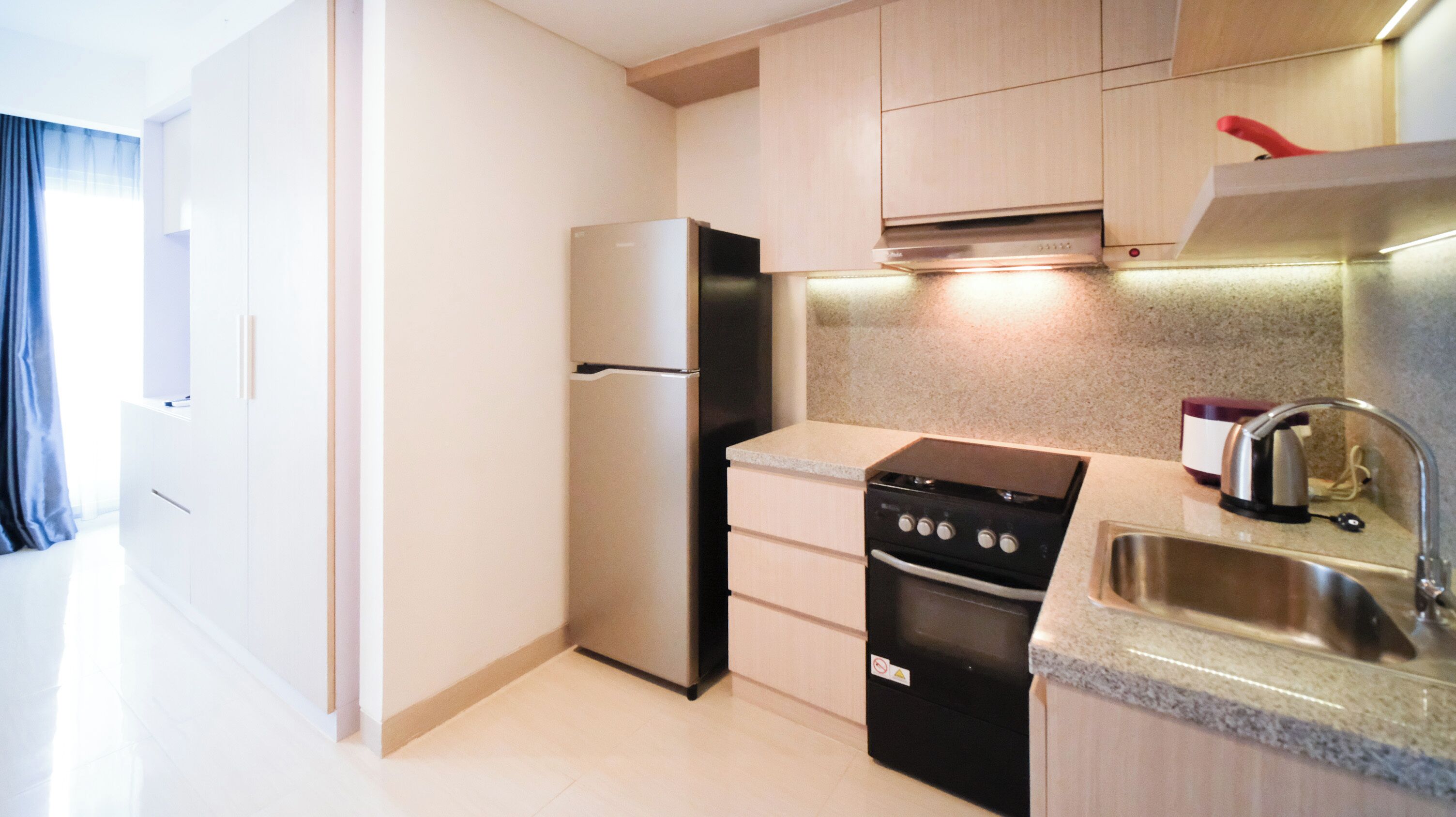 A modern kitchen with a refrigerator, stove, dishwasher, and granite countertop.