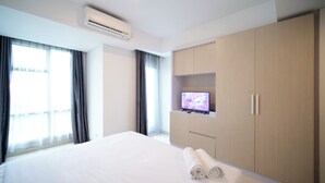A hotel room with a bed, a TV, and a wardrobe. - Modern And Comfy Studio At Grand Sungkono Lagoon Apartment (Surabaya)