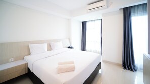 Relax in a spacious room with a large bed, bedside table, and lamp.