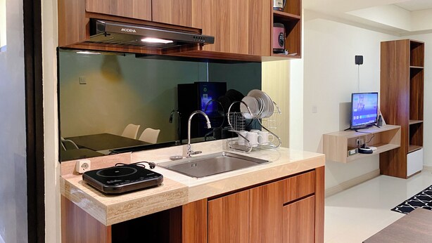 Een moderne keuken met houten kastjes, een inbouwoven, een koffiezetapparaat en een laptop op een bijzettafeltje.