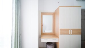 A minimalist bedroom with a wooden wardrobe, a small bedside table, and a single drawer. - Comfy 2Br At Taman Melati Surabaya Apartment (Surabaya)