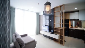 A modern living room with a sofa, a TV, and a wooden shelving unit. - Comfy 2Br At Taman Melati Surabaya Apartment (Surabaya)