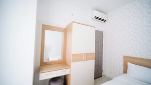 A bedroom with a bed, a wardrobe, a mirror, and an air conditioning unit. - Comfy 2Br At Taman Melati Surabaya Apartment (Surabaya)