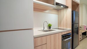 Eine moderne Küche mit einer Spüle aus Edelstahl, einem Einbauofen und einem schwarzen Kühlschrank.