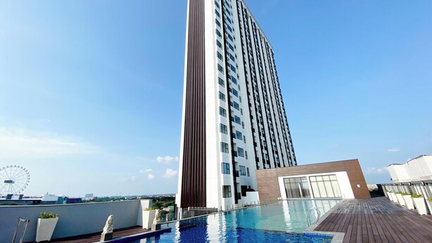 Ein Hochhaus mit Poolbereich auf dem Dach, inklusive Pool, Holzterrasse und einem Riesenrad im Hintergrund.