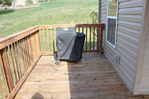 A wooden deck with a covered grill and a window.