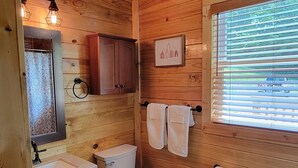 Baño de cabaña de madera con inodoro, lavamanos y armarios.