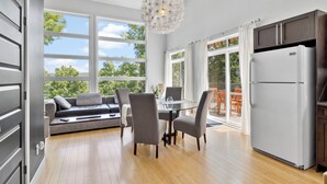 A modern kitchen with a built-in refrigerator, a dining area with a glass table, and a seating area with a sofa and chairs.