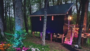 A cabin with a wooden deck and a staircase leading to a second level. - Wall of Windows Treehouse-Romantic Woodland Retreat-Escape (Doyle)