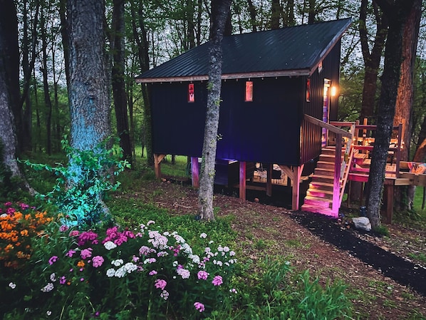 A cabin with a wooden deck and a staircase leading to a second level. - Wall of Windows Treehouse-Romantic Woodland Retreat-Escape (Doyle)