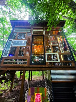 A treehouse with multiple levels, large windows, and a wooden exterior.
