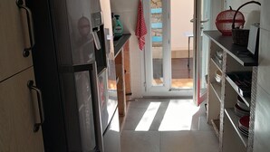 A compact kitchen with a refrigerator, a sink, and a microwave. A red towel hangs on the door, and a basket is on the counter. - 1 Bedroom Apartment in Cassis (Cassis)