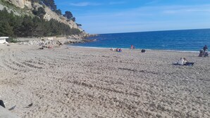 A sandy beach with people relaxing and walking along the shore. - 1 Bedroom Apartment in Cassis (Cassis)