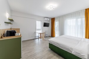 Una habitación de hotel con cama, escritorio con silla, televisión y estación de café.