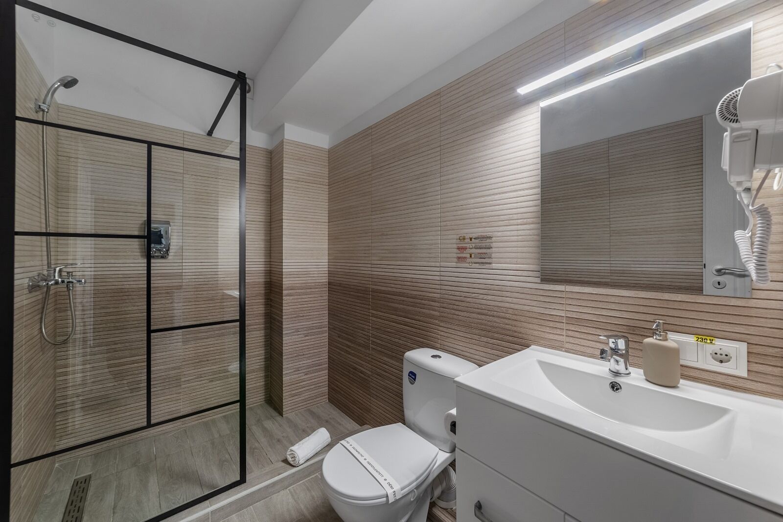Uma casa de banho moderna com cabine de duche em vidro, sanita e lavatório com espelho em cima.