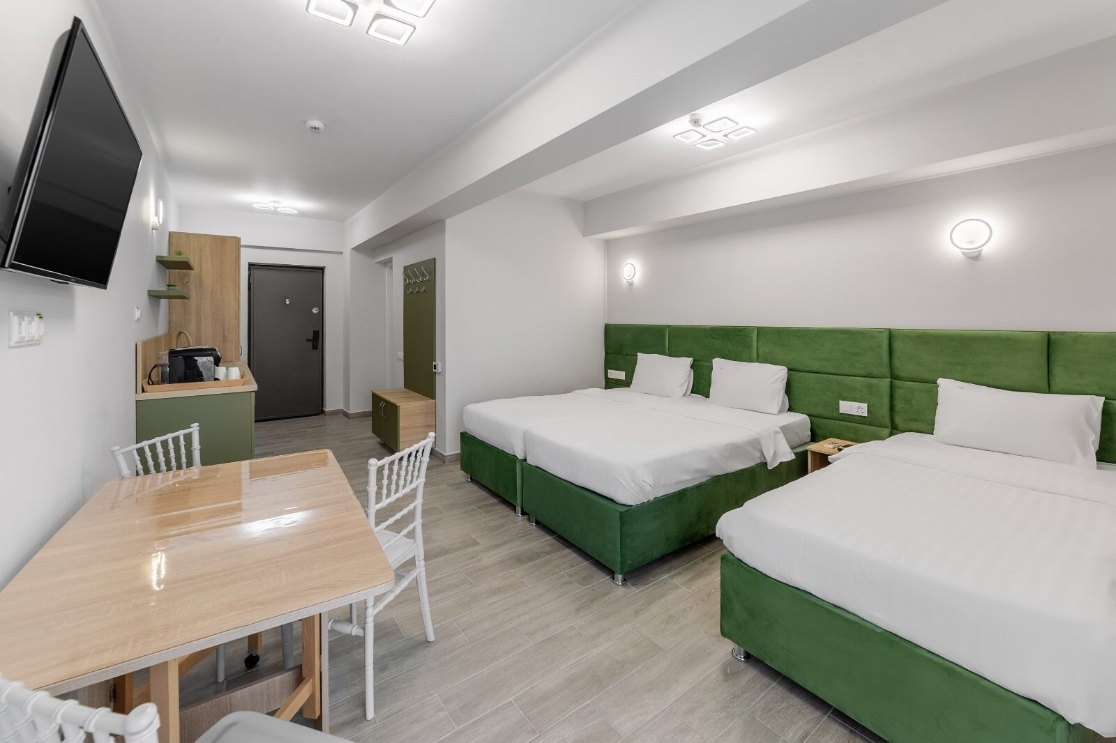 Quarto de hotel moderno com duas camas, uma mesa de jantar e televisão.