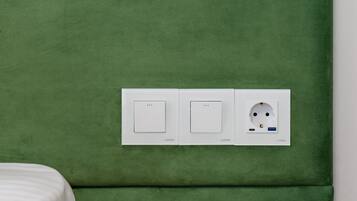 A green upholstered headboard with two white switches and a power outlet with USB and USB-C ports.