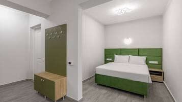 A modern bedroom with a green upholstered bed, a wooden bench, a wardrobe, and a bedside table.