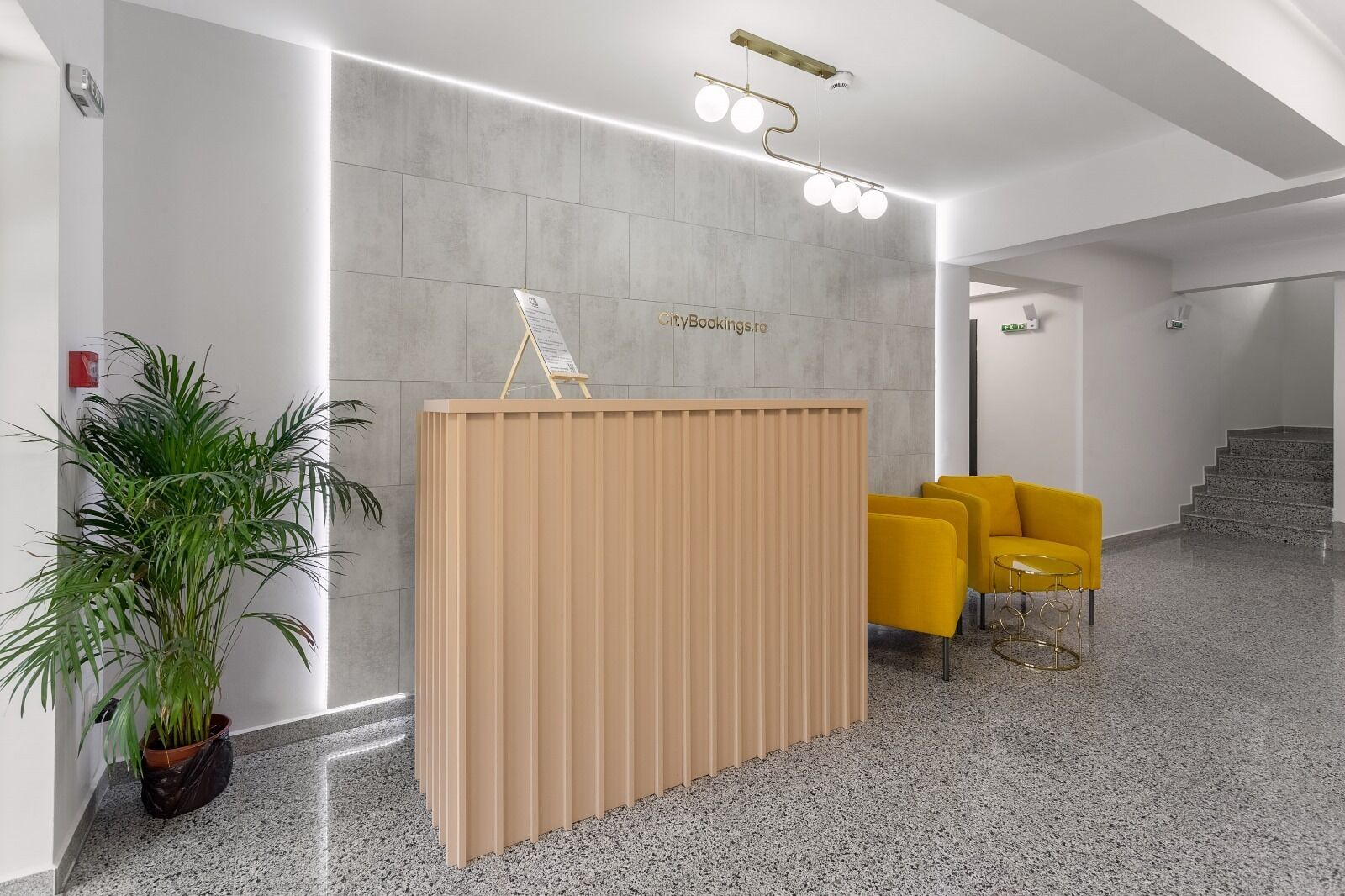 A reception area with a wooden partition, a potted plant, and yellow chairs.