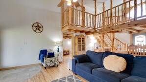 Ein geräumiges Wohnzimmer mit einem blauen Sofa, Holzboden, einer Treppe und einer Wanddekoration mit Sternen.