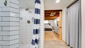 Ein Badezimmer mit weiß gefliesten Wänden, einer Dusche mit gestreifter Duschvorhang und einer Holzboden.