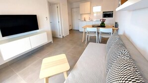 Ett modernt vardagsrum med en platt-TV, ett soffbord i trä och en mönstrad soffa.