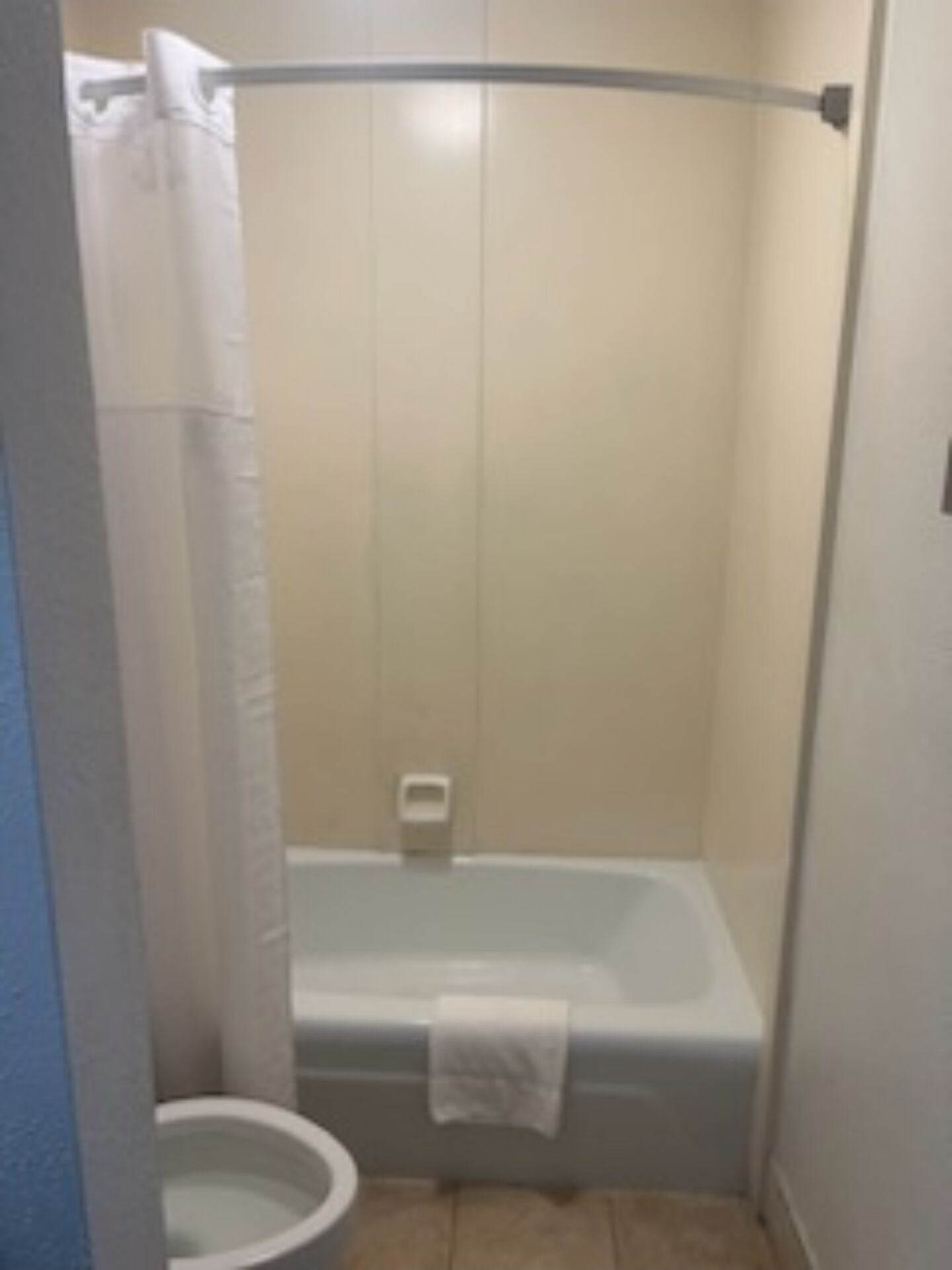 A small, enclosed bathroom with a toilet, a bathtub, and a shower curtain.