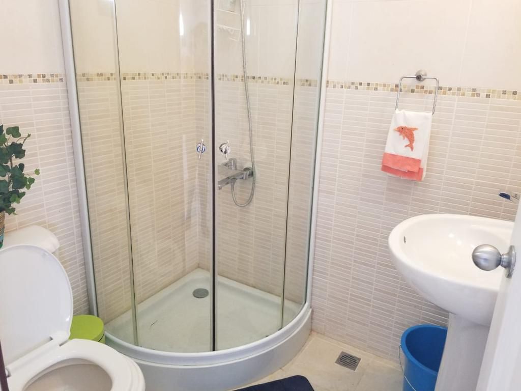 A bathroom with a glass-enclosed shower, a toilet, and a sink.