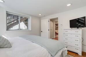 A bedroom with a bed, a dresser, a television, and a window with blinds. - Commuter-Friendly Seattle Apartment! Dogs Welcome (Seattle)