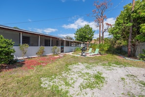 A single-story building with a covered patio area, a small garden with various plants, and a green lawn. - Sea Side Vacation Home - By 5 beaches (Venice)