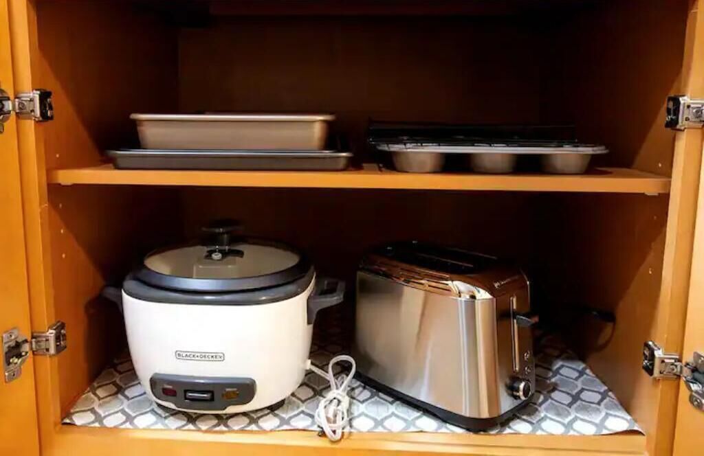 Una cocina con una olla de cocción lenta, un tostador y una bandeja en la encimera.