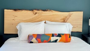 A bed with white bedding and two pillows, one plain white and one multicolored, against a teal wall with a wooden headboard. - Luxe Berkshires Ski Retreat w/ Fireplace, King Bed, Chef's Kitchen, Washer/Dryer (Great Barrington)