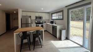 A modern kitchen with white cabinets, stainless steel appliances, and a large sliding glass door leading to a backyard. - Luxe Berkshires Ski Retreat w/ Fireplace, King Bed, Chef's Kitchen, Washer/Dryer (Great Barrington)