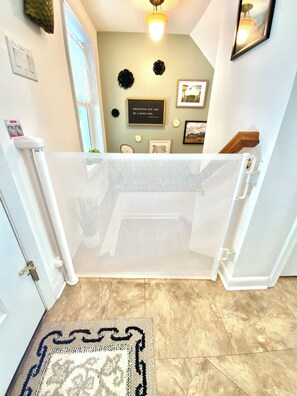 A doorway with a white mesh screen, a patterned rug, and a wall with framed pictures and a motivational quote.