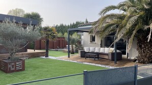 A patio area with a wooden deck, a built-in bench, and a pergola. - Villa 290m2, Piano, Piscine et Spa, Parc Arboré Entre Bordeaux et St Emilion (Sallebœuf)