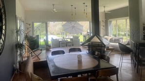 A spacious living area with a large round table, comfortable seating, and a view of the outdoors. - Villa 290m2, Piano, Piscine et Spa, Parc Arboré Entre Bordeaux et St Emilion (Sallebœuf)