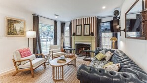 Ein Wohnzimmer mit Kamin, einer Couch, einem Sessel und einem Couchtisch.