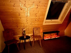 Una habitación acogedora con techo de madera, chimenea y ventana.