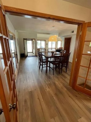 Un'ampia sala da pranzo con tavolo e sedie in legno, ampie finestre e una lampada a sospensione.