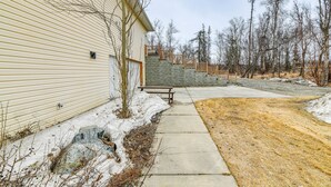 Il s’agit d’une propriété résidentielle dotée d’un escalier en pierre menant à une terrasse en bois, d’un chemin en béton et d’un sol recouvert de neige.