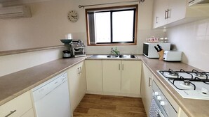 Une cuisine de taille réduite équipée d’un lave-vaisselle, d’une cuisinière, d’un évier et d’une fenêtre.